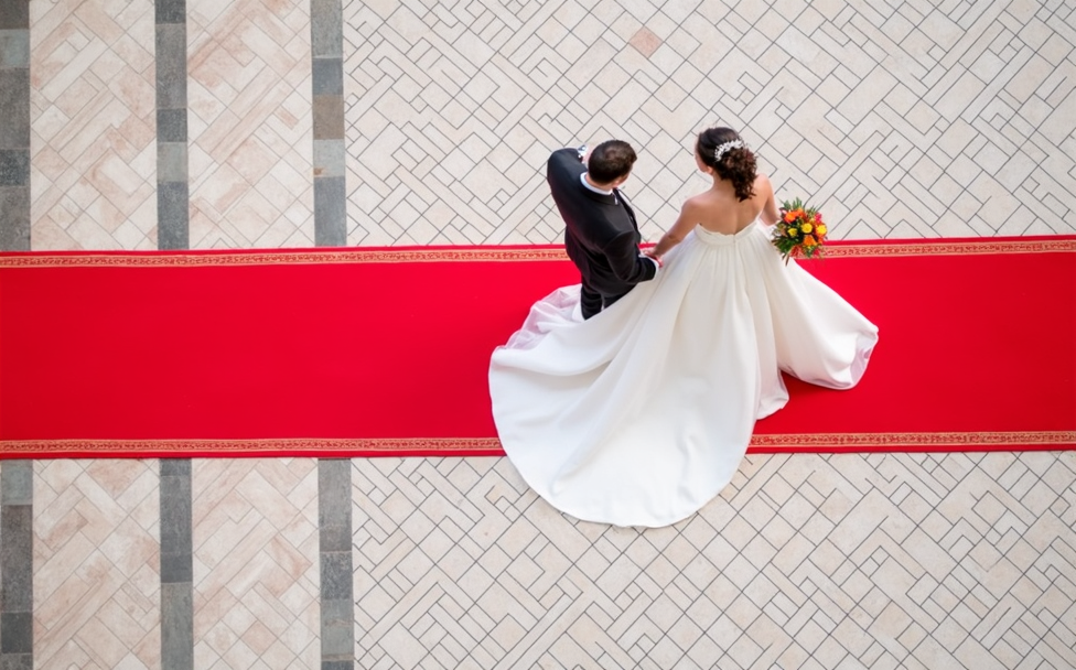 Dos recién casados caminan por encima de una alfombra roja. Plano cenital.